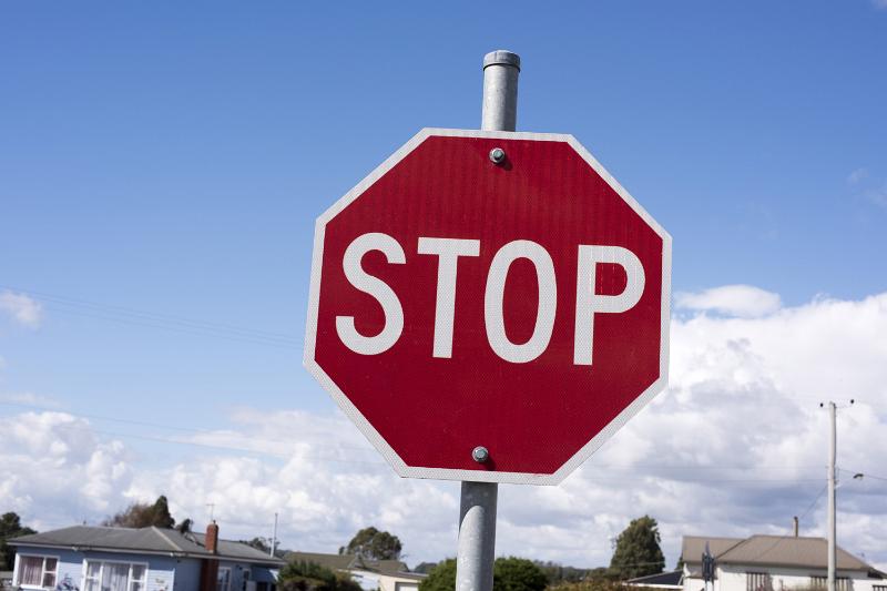 Free Stock Photo: STOP sign on a pole viewed in close-up from low angle with suburban houses in background