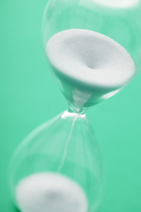 Free Stock Photo: Close up view of hour glass with white sands pouring into lower part against a green background