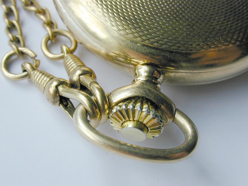 Free Stock Photo: Close up of the silver winder and chain on a vintage pocketwatch with an embossed textured case