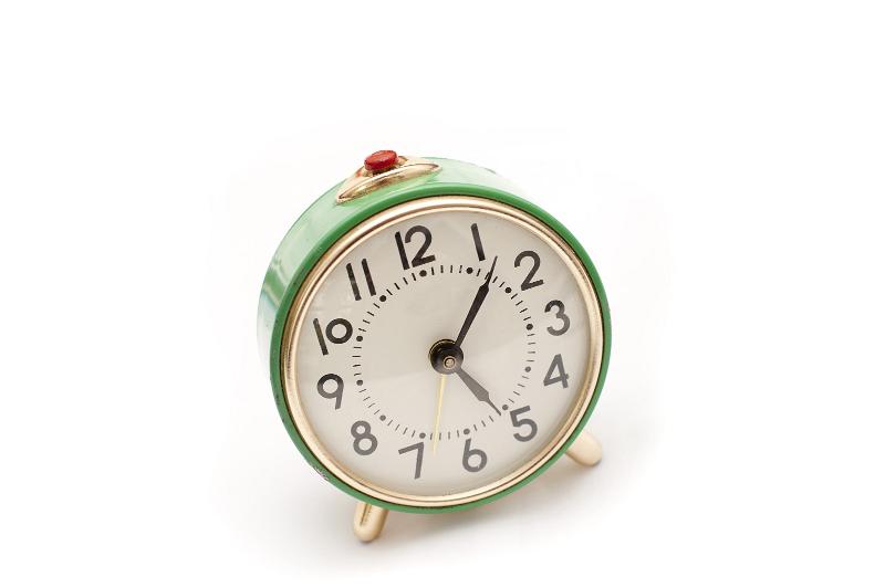 Free Stock Photo: Still Life of Round Green Vintage Wind Up Alarm Clock with Red Snooze Button on Top with White Background, Time Shown is Seven Minutes Past Five