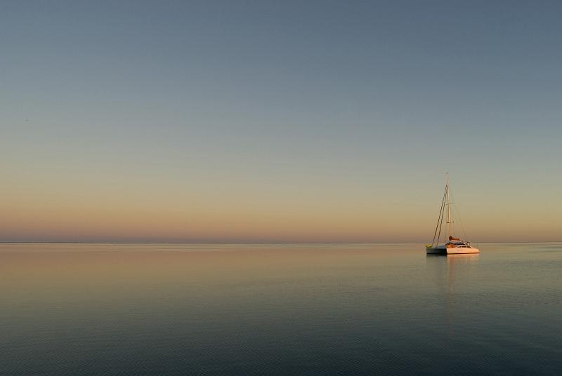 Free Stock Photo: A boat anchored on an almost mirror flat lagoon at sunset