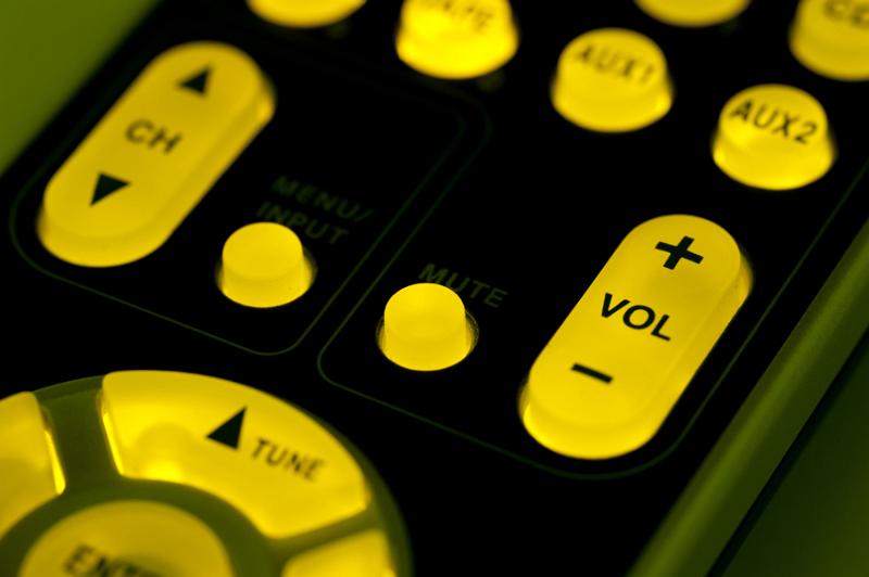 Free Stock Photo: Backlit remote control keypad with glowing yellow buttons with focus to the Volume