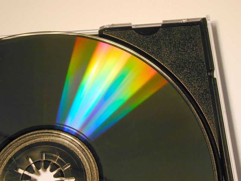 Free Stock Photo: Iridescent display of light on a DVD or CD disc in a colorful spectrum as it lies in its plastic box