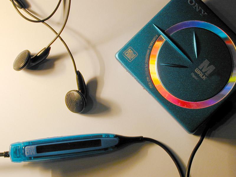 Free Stock Photo: Blue plastic Mini DisÑ Sony personal portable music player with controls on cord and black earbuds on white table surface shot from above