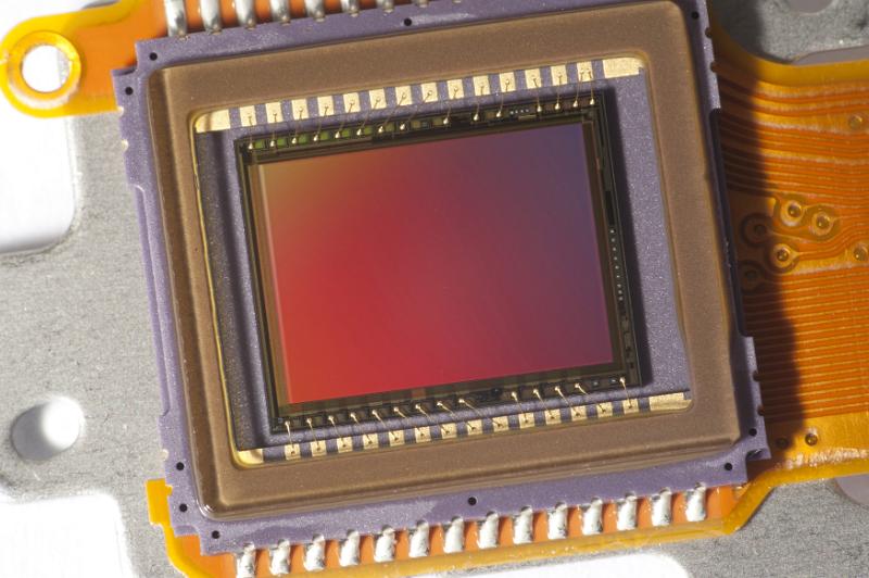 Free Stock Photo: Video sensor chip or image sensor with reddish surface color and yellow cord, close-up on white background