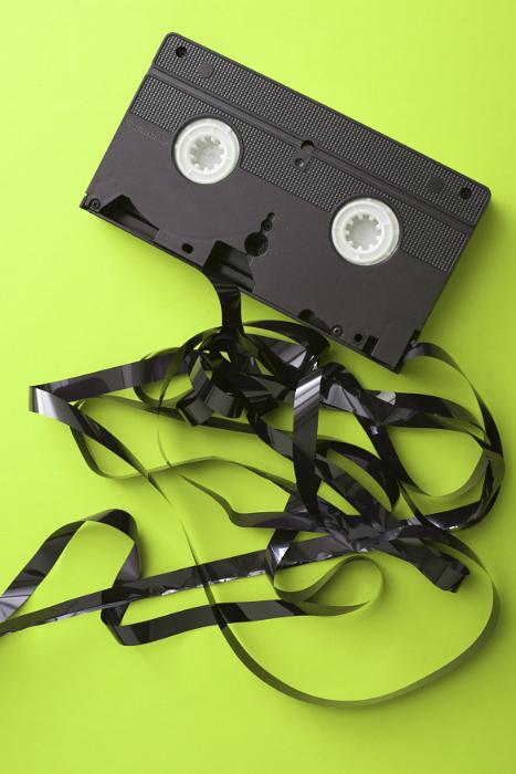 Free Stock Photo: Tangled destroyed video tape that has unwound from the cassette on a lime green background in a communication and entertainment concept
