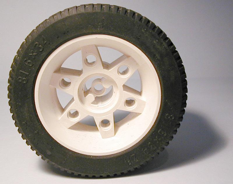 Free Stock Photo: toy car tyre with a white rim and hub and new tread standing upright on a grey background with shadow