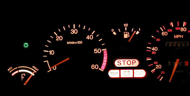 Free Stock Photo: Close up of illuminated dashboard with fuel gauge and speedometer against a black background