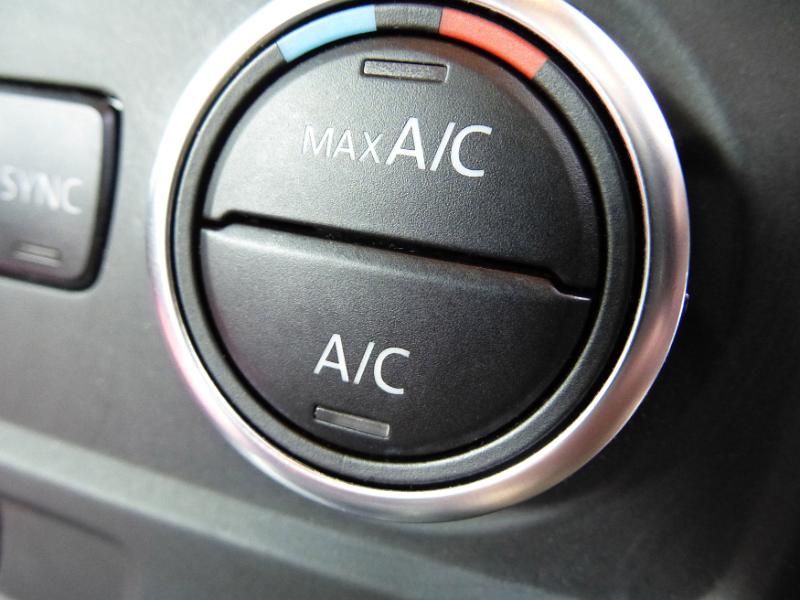 Free Stock Photo: Circular air conditioning control knob on the black vinyl dashboard in a car in a close up view
