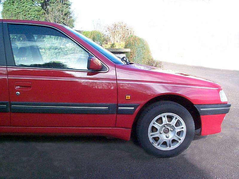 Free Stock Photo: Side front view of a red sedan car with spoked wheels parked on asphalt
