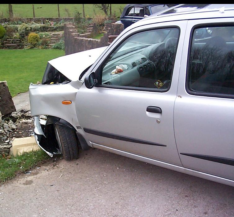 Free Stock Photo: Smashed car pulled over to the side of a road with its bonnet concertinaed and wheel hub destroyed