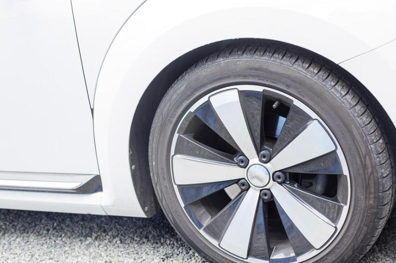Free Stock Photo: Modern low profile car tyre with alloy rim with white spokes on a white vehicle parked on tarmac, close up view