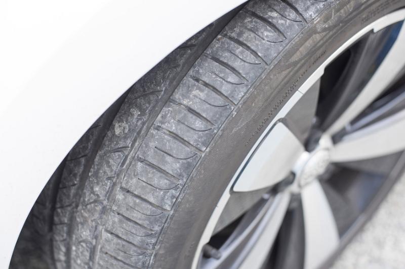 Free Stock Photo: Close up view of a used car tyre and tread on a parked white vehicle viewed from above