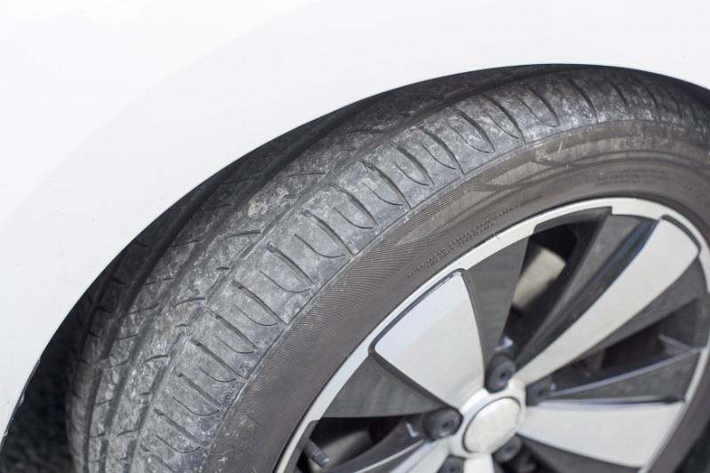 Free Stock Photo: Car wheel detail on a white vehicle with focus to the treads of the tyre showing usage and wear, high angle close up view