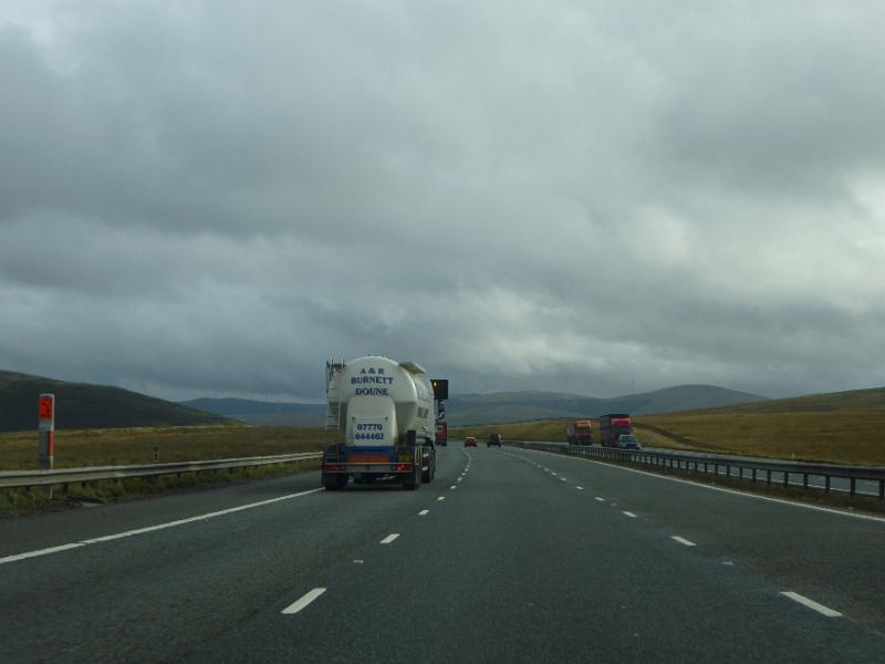 Free Stock Photo: Back view of lonely truck riding on highway in fields on cloudy gloomy day.