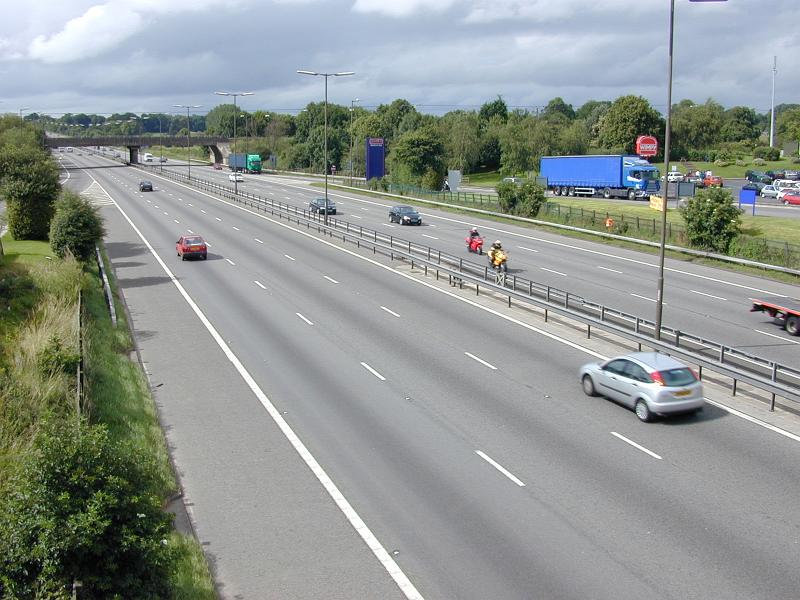 Free Stock Photo: Cars travelling on a three lane motorway in countryside with a garage or service station on the one side