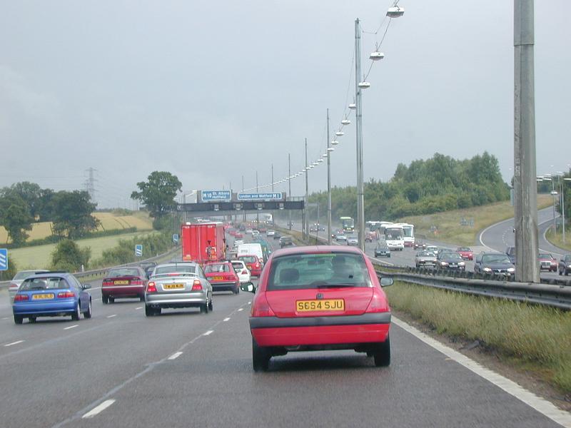 Free Stock Photo: Traffic driving on a motorway from a driver perspective with a three lane highway with cars and trucks flowing in either direction on an overcast day