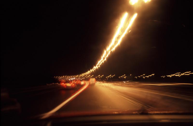 Free Stock Photo: Traffic blur on a highway at night with a curving row of illuminated street lamps disappearing into the distance with motor vehicles in motion