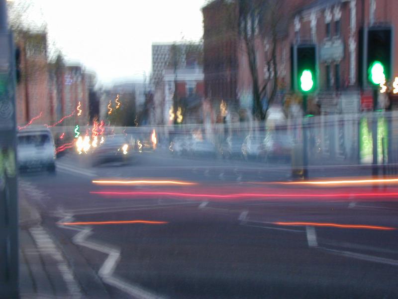 Free Stock Photo: Blurred background of a city street at dusk with light trails of traffic and a green traffic light at an intersection