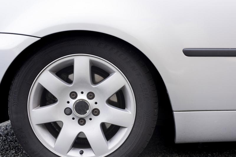 Free Stock Photo: Car wheel on a modern white vehicle viewed from the side showing the spokes of the hub and rim in a close up cropped view with copy space