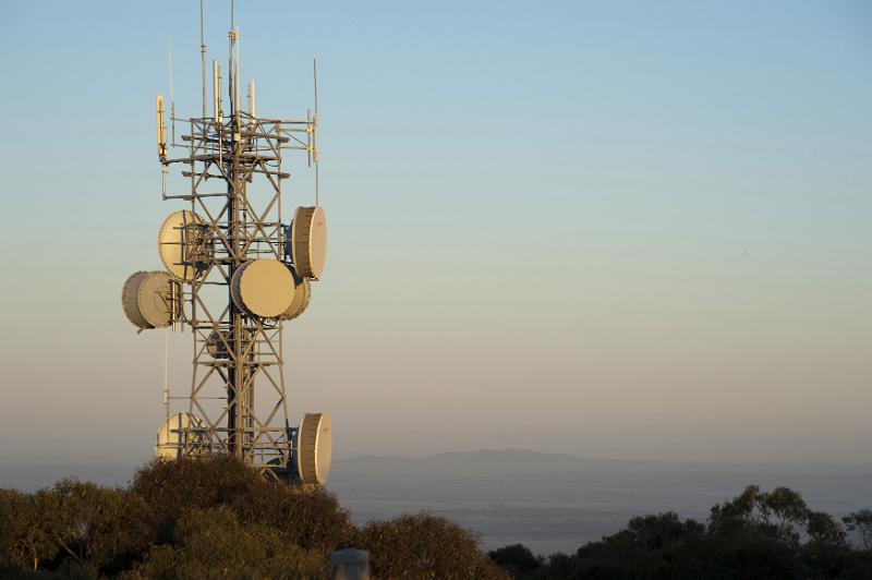 Free Stock Photo: Cellular or mobile phone communications mast or tower with dish antennae with transmitters and receivers on a hilltop at sunset