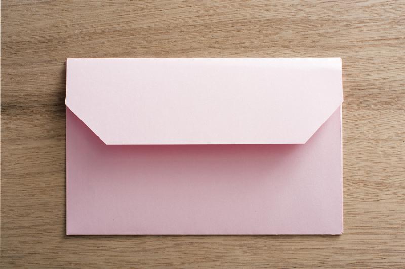 Free Stock Photo: Pink envelope with an open flap lying face down on wood in a communications or correspondence concept