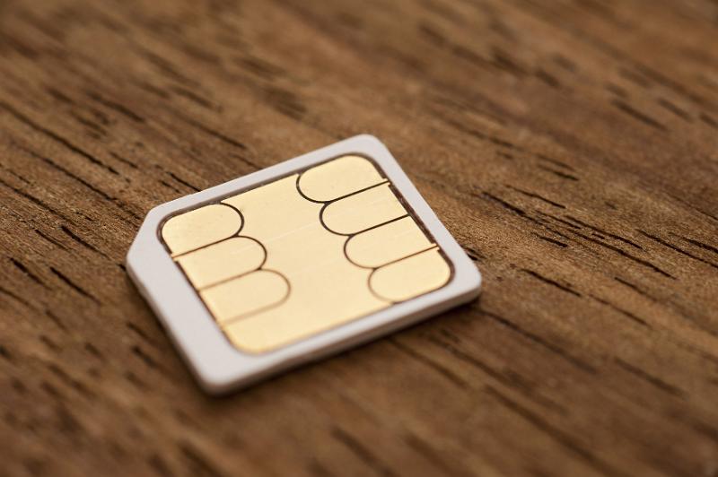 Free Stock Photo: Micro-sim card for a mobile phone on a wooden background with shallow dof and partial focus in a communication concept