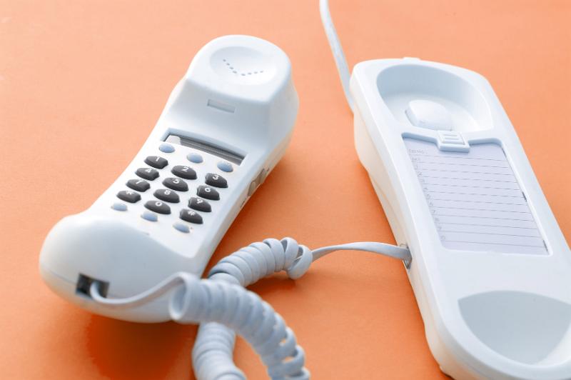 Free Stock Photo: Telephone receiver left off the hook for privacy or because the recipient of the call is busy with something else over an orange background