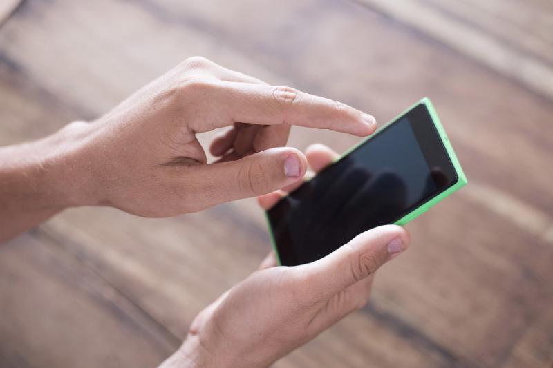 Free Stock Photo: A close up of a man's hands using and typing on a modern black smart phone.