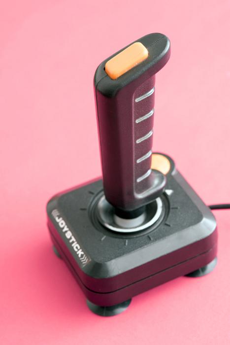 Free Stock Photo: Joystick with cable standing against pink background