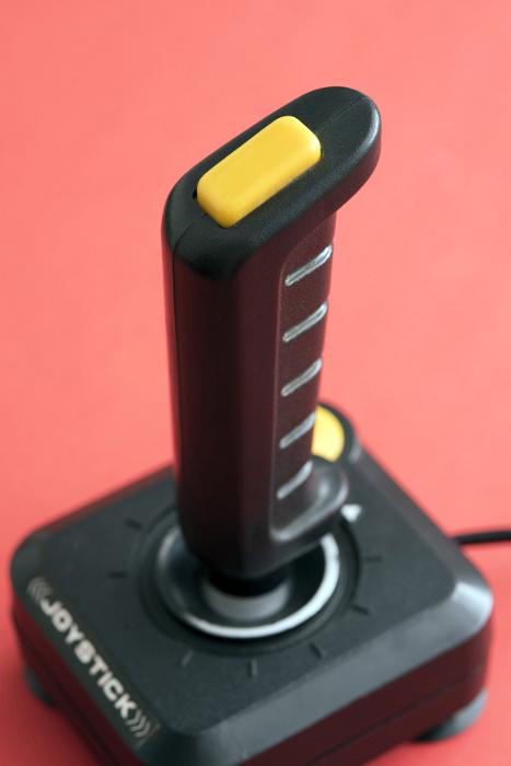 Free Stock Photo: Retro gaming joystick or controller for playing video games with handle and buttons on a red background viewed high angle in an entertainment concept
