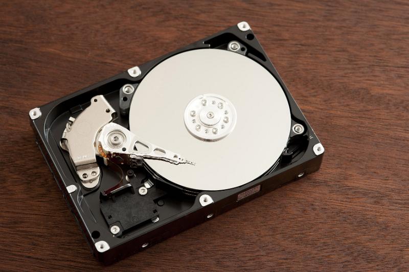 Free Stock Photo: Open 3.5 inch hard disk drive HDD with head over disks surface, close-up from above on dark wooden table