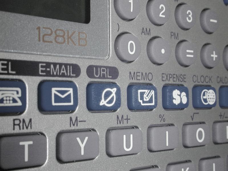 Free Stock Photo: Close up of grey plastic calculator and computer and phone with many blue and grey buttons with slightly blurred edges
