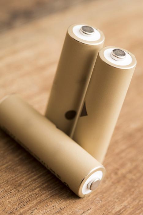Free Stock Photo: Three natural coloured AA rechargeable cell batteries isolated on a brown timber background.