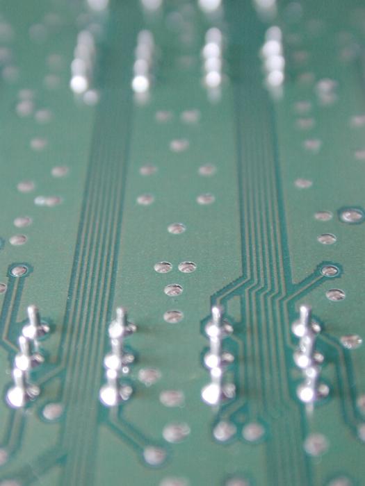 Free Stock Photo: A close up of the underside of an electronic circuit board showing deductive tracks, wiring and solder joints.