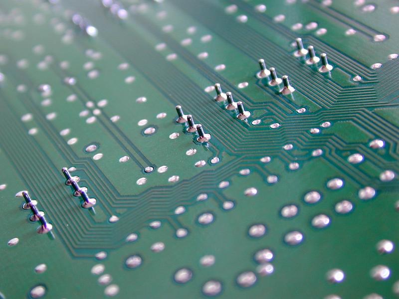 Free Stock Photo: Close up detail of the conductive tracks and solder on the underside of a green circuit board.