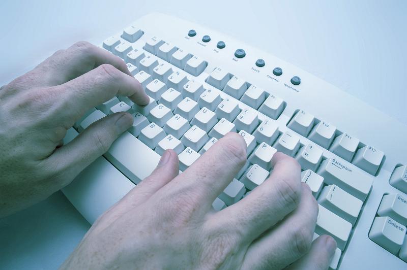 Free Stock Photo: hands typing at a computer keyboard with a cross processed effect applied