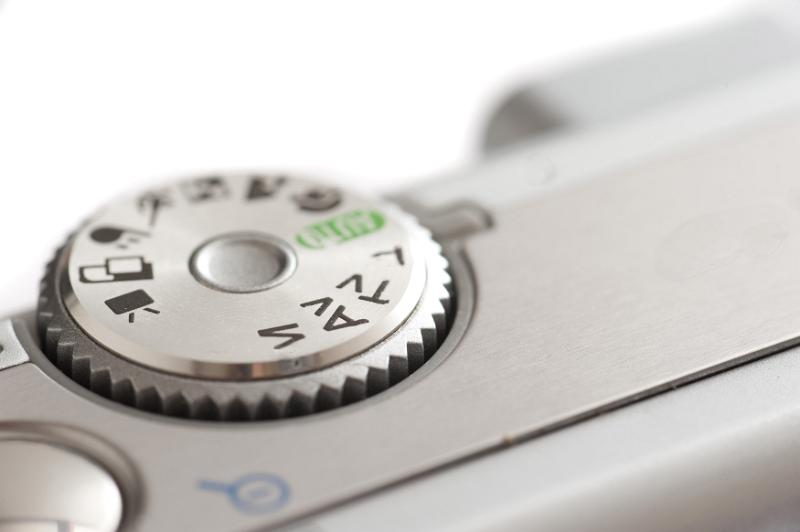 Free Stock Photo: Control dial on a silver compact digital camera showing the various modes and programs on the wheel