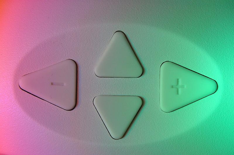 Free Stock Photo: Direction control pad with arrows in the up-down and left-right positions for increasing and decreasing a parameter in a colorful gradient of pink through green light