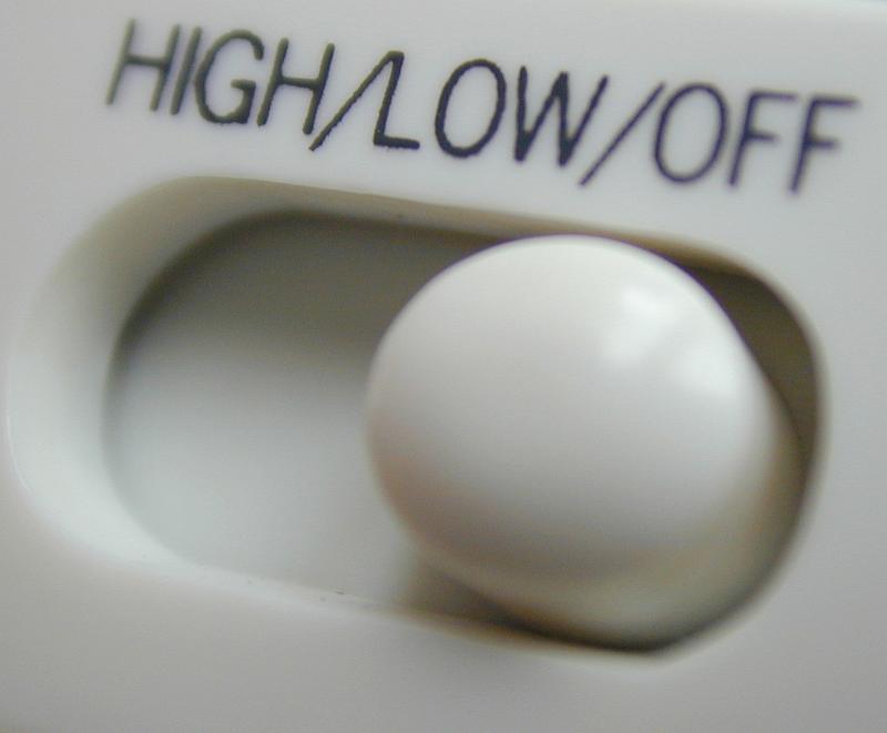 Free Stock Photo: White plastic slider level switch annotated High - Low - Off in a close up view on the button on electronic equipment