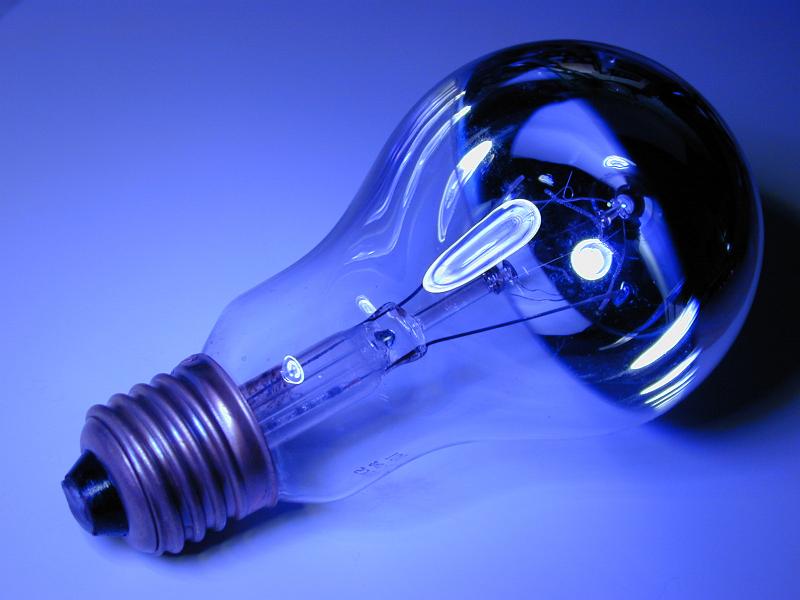 Free Stock Photo: Electric light bulb with a screw mount lying on its side viewed in colorful blue light in a power and energy concept