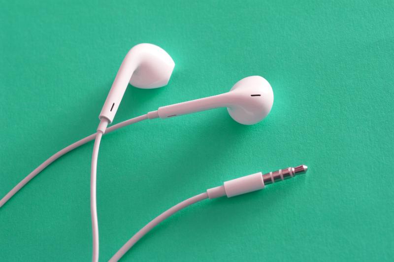 Free Stock Photo: Set of white Apple earpods and connector lying on a green background in a communication and audio entertainment concept