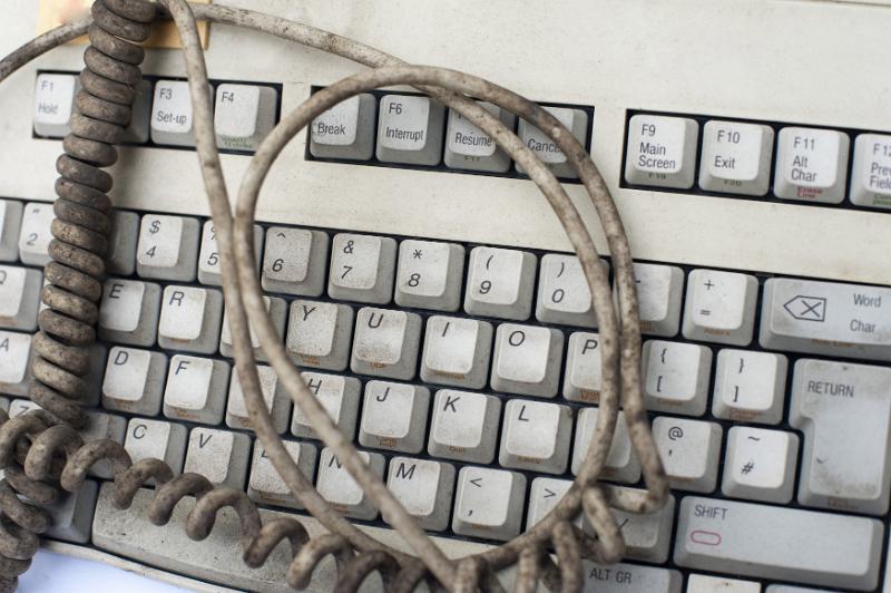 Free Stock Photo: Grungy dirty old white computer keyboard with the filthy cord coiled on top in a close up view in a communication concept