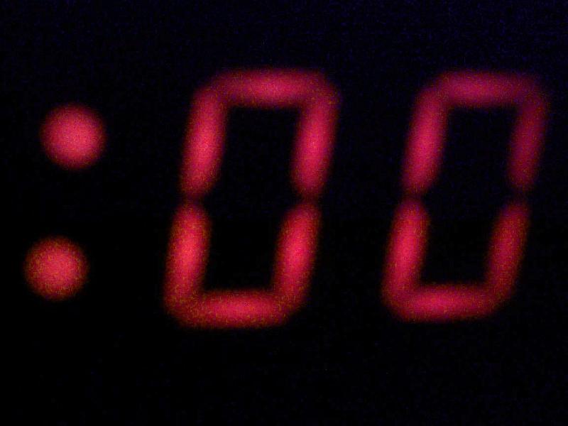 Free Stock Photo: Blurred red digits of double zero on display of a clock or music player, glowing out of black background