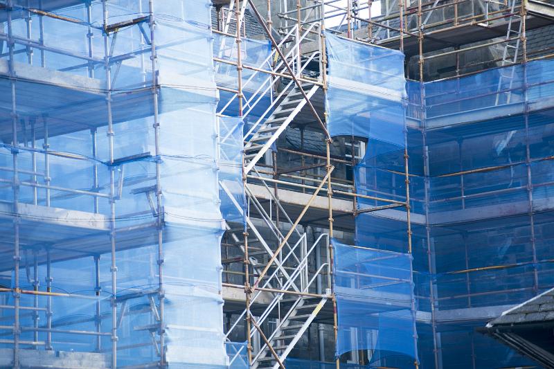 Free Stock Photo: Commercial high-rise building maintenance and repair concept with scaffolding and protective plastic sheeting obscuring the sides of a building