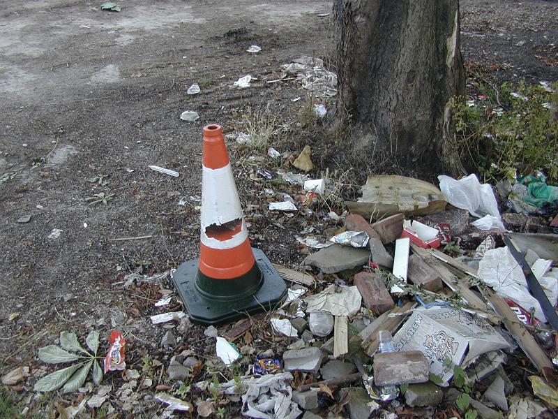 Free Stock Photo: Damaged traffic cone and pile of rubbish alongside a wooden pole in a concept of pollutants and environmental pollution