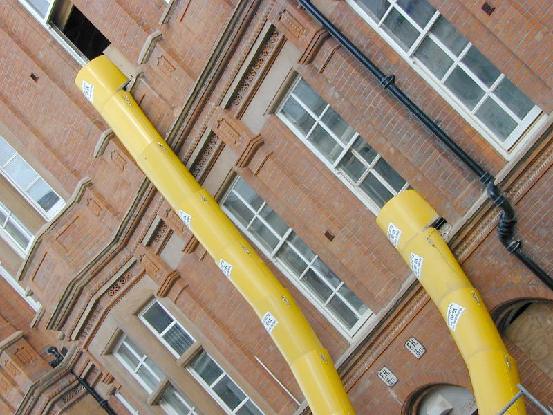 Free Stock Photo: Yellow waste removal sleeves attached to building windows for collecting the construction garbage during the renovation process