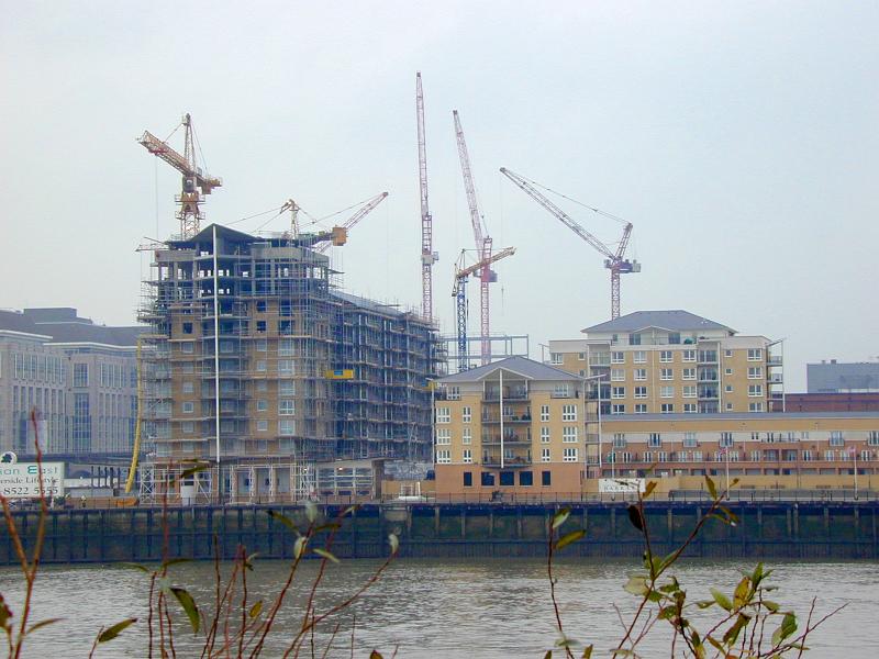 Free Stock Photo: Waterfront urban construction of high-rise buildings surrounded by lots of industrial cranes viewed over the water on a misty day