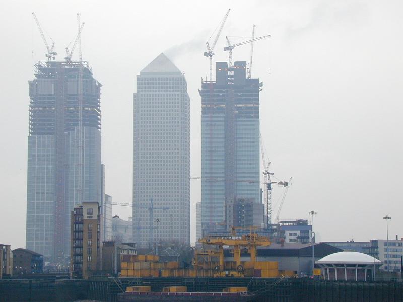 Free Stock Photo: Industrial construction on three tall skyscrapers in an urban environment with heavy duty machinery and tall cranes against a misty skyline
