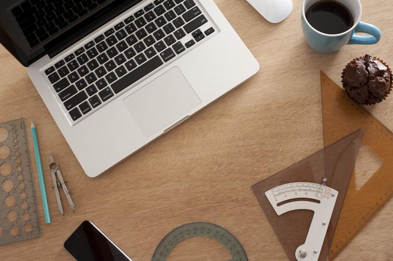 Free Stock Photo: Engineers workplace with laptop computer, various rulers and a mug of coffee on the desk, viewed from above